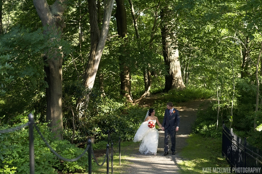 tupper manor wedding photo of bride and groom walking through woodland at back of venue
