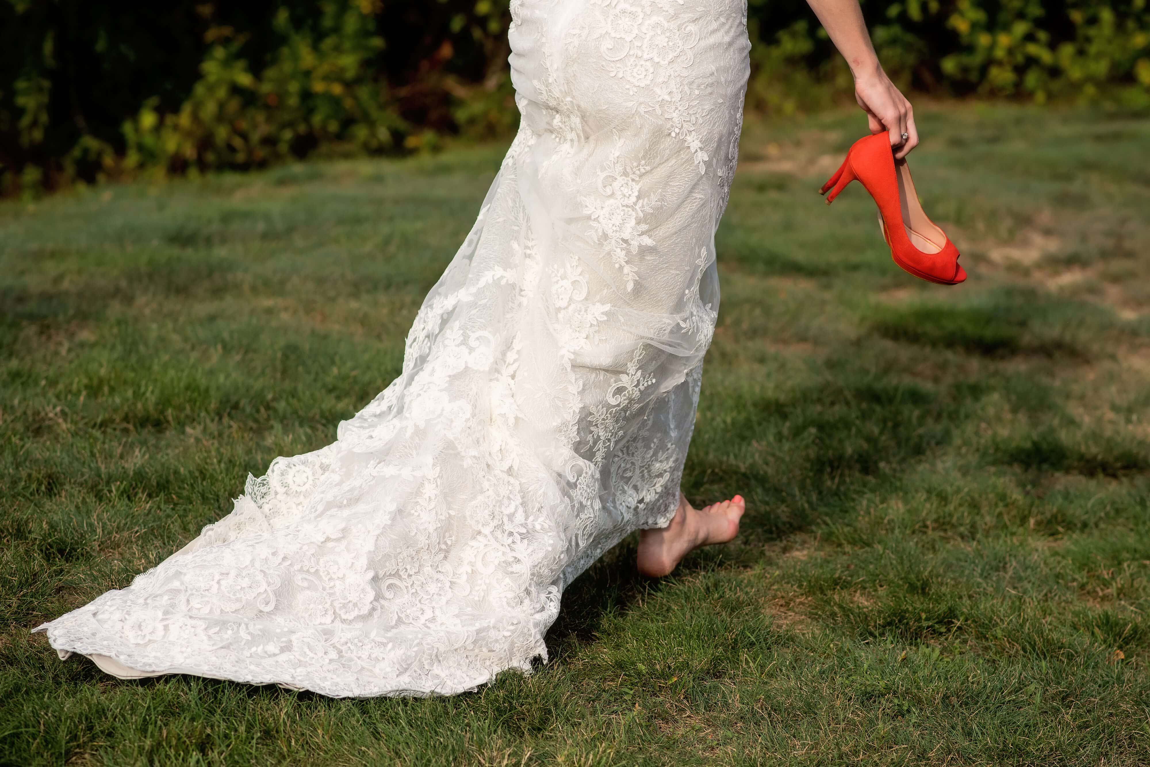 casual bride at mart has vineyard wedding carrying her red shoes after ceremony