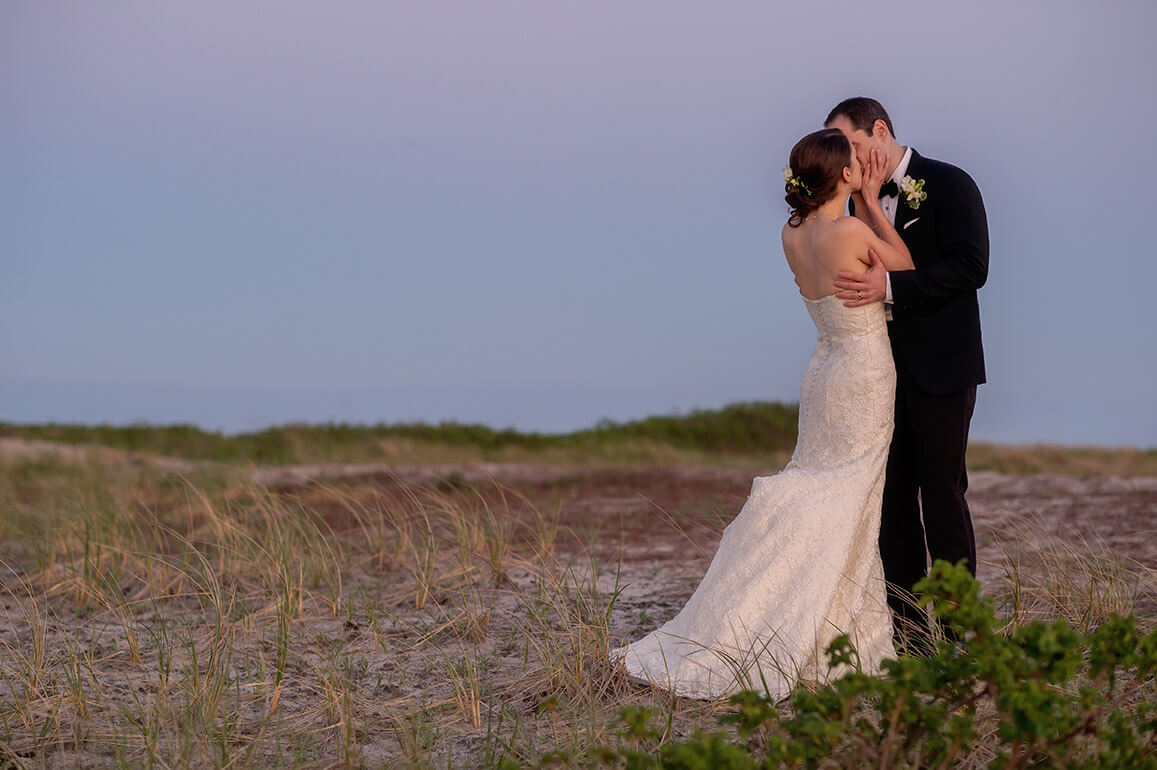 photo of bride and groom at sunset kissing on sand dune at wychmere wedding in harwichport