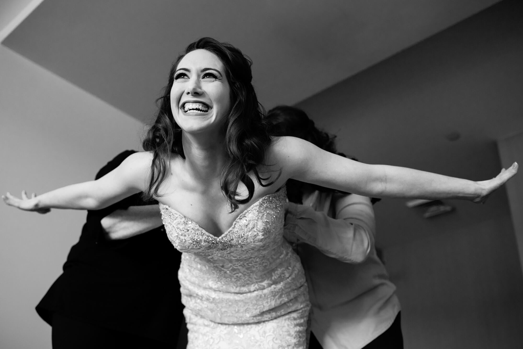 fun photo of happy bride getting into dress superman pose