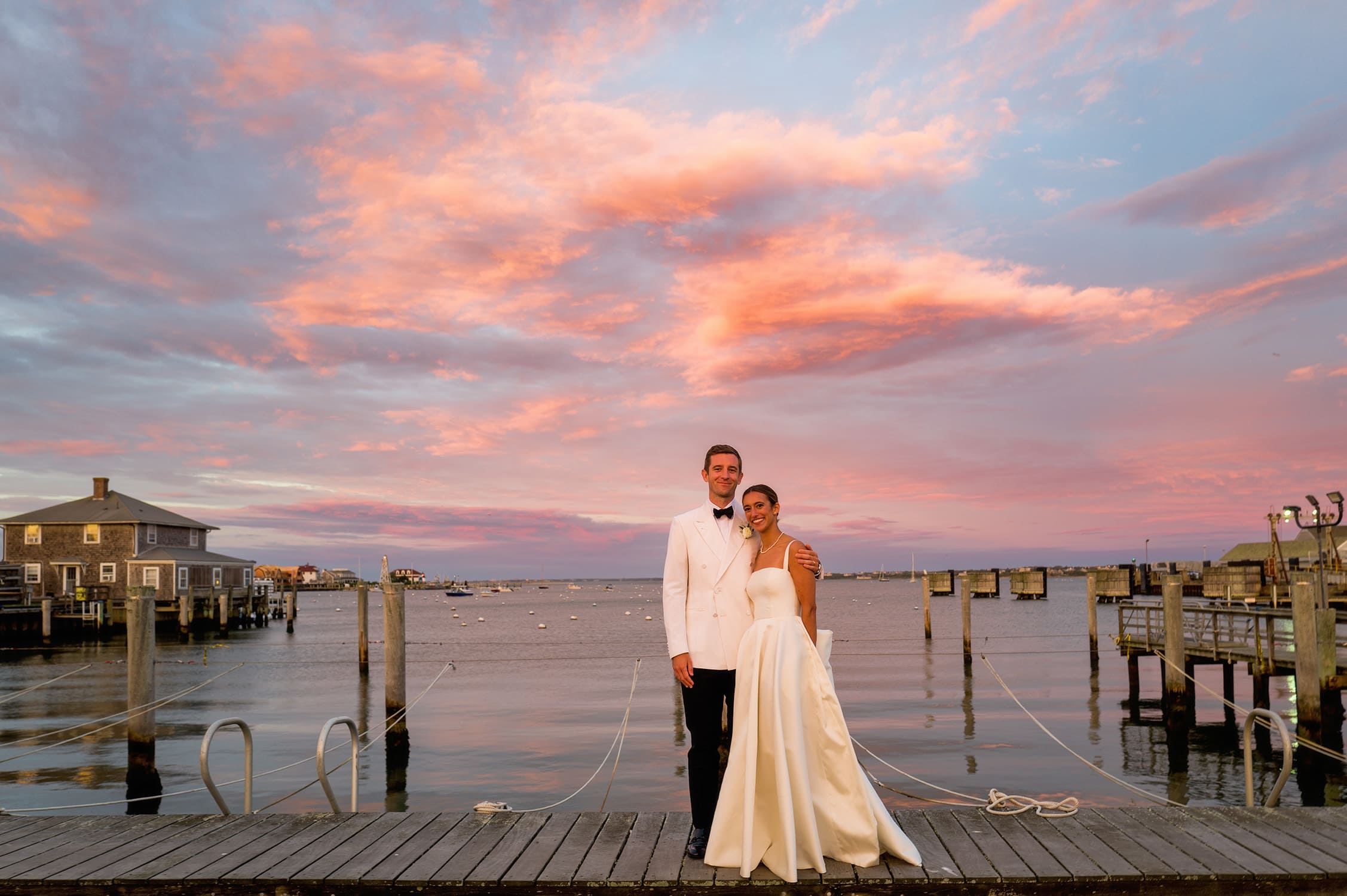 nantucket yacht club wedding bride and groom pose on dock at sunset